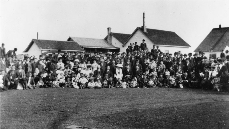 The Japanese Consul and wife with a large group of Japanese people in front of houses